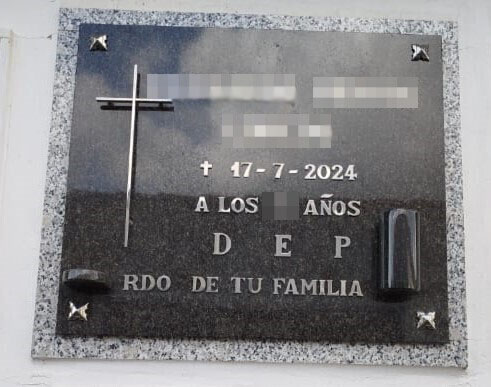 Lápida en negro con inscripción en letra adhesiva, cruz de acero inoxidable y búcaro de granito